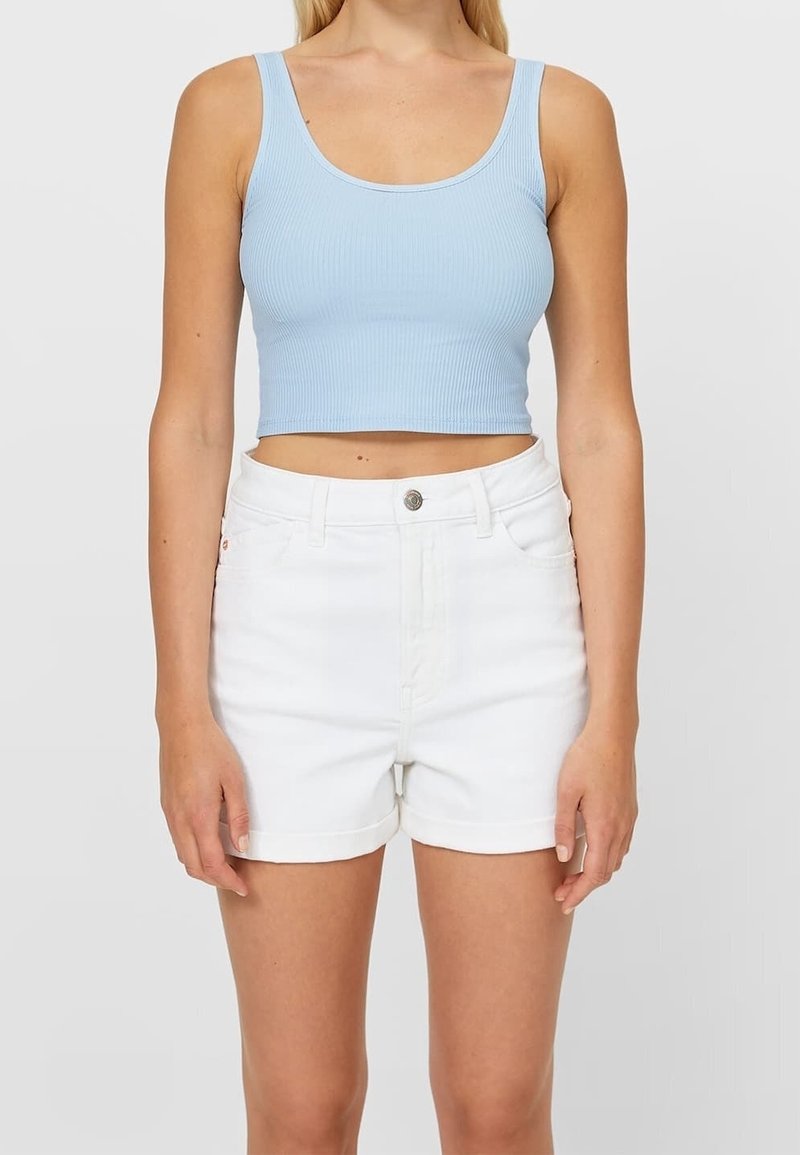 Lichtblauw geribbeld crop top gecombineerd met witte denim shorts met opgerolde zoom en knoopsluiting aan de voorkant. Gladde textuur, casual ontwerp.