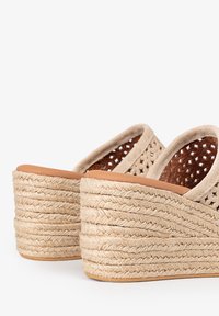 Sandalias de cuña tejidas beige con una plataforma de yute texturizado, lados abiertos y un material superior suave con textura de ante.