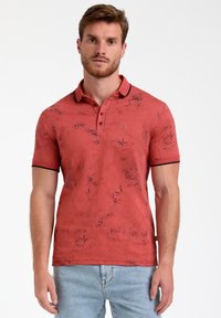 Polo rosso con un motivo floreale, maniche corte e colletto a coste nero. Presenta bottoni e un logo sul lato sinistro del petto.