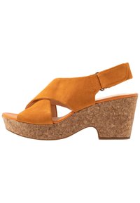 Sandalo wedge arancione in suede con tacco in sughero, caratterizzato da cinturini incrociati e una cinghia alla caviglia regolabile per una vestibilità sicura.