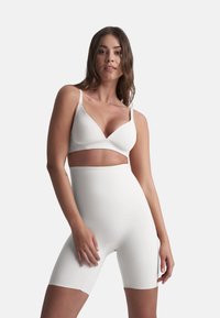 Conjunto de lencería blanca sin costuras que incluye un sujetador suave y moldeado con tirantes ajustables y pantalones cortos de cintura alta en un material liso y elástico.