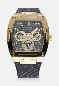 Reloj cuadrado en tono dorado con una correa negra texturizada, que presenta una esfera oscura, tres subesferas y acentos dorados en los marcadores de horas y las agujas.