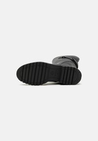 Bottines noires avec une tige en cuir texturé, dotées d'une semelle en caoutchouc à rainures pour une meilleure adhérence et d'une fermeture éclair sur le côté.