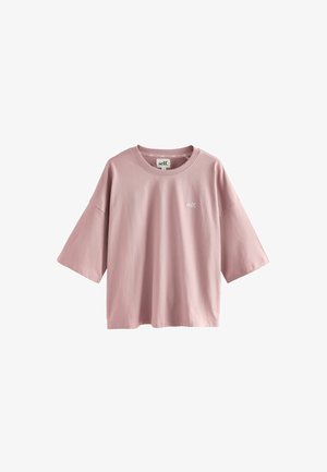 Rosa Baumwoll-T-Shirt mit lockerer Passform, überschnittenen Schultern und kurzen Ärmeln. Verziert mit einem kleinen "self."-Logo auf der Brust. Glatte Textur.