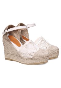 Beige espadrilky na vysokém podpatku s tkaným juty podpatkem, bílým krajkovým předním dílem a popruhem kolem kotníku. Hladká vnitřní podšívka, kulatý tvar špičky.