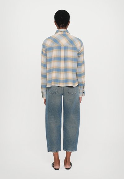 Rutete skjorte i blå, gul og kremfarge med lange ermer, krage og avslappet passform, kombinert med vide denimjeans i lys vask.