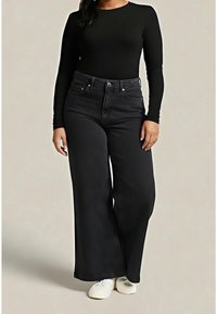 Jean noir à jambes larges avec taille haute, poches avant et fermeture par boutons. Associé à un haut noir à manches longues et des baskets blanches.