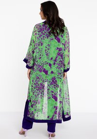 Lang, gennemsigtig kimono i grøn og lilla leopardmønster. Har kontrasterende marineblå kanten. Strømmende design og løse ærmer. Blødt, let stof.