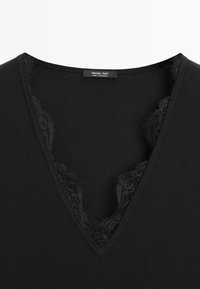 Czarny top z dekoltem w serek i delikatną koronkową lamówką przy dekolcie, z metką Massimo Dutti, wyprodukowany w Maroku.