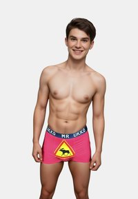 Boxers rosas con una cinturilla negra que presenta el texto "MR UKKO" y una señal de advertencia amarilla con un gráfico de un alce en la parte delantera.