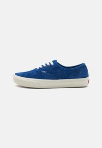 Blue suede low-top sneakers with white laces, cream rubber sole, and a small red logo on the heel. Designed for casual wear.