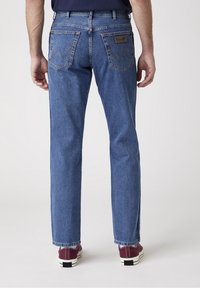 Jeans de mezclilla azul con diseño de pierna recta, que cuentan con una pretina, dos bolsillos traseros con costura en zigzag y una etiqueta de cuero en el bolsillo derecho.