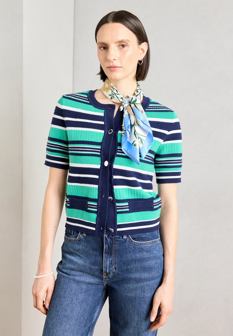 Cardigan à manches courtes rayé en vert, bleu et marine. Texture côtelée avec fermeture à boutons et poches plaquées. Assorti à un foulard en soie à imprimé floral.