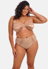 Beige lingerie setti, joka sisältää satiinisen rintaliivimallin, jossa on pitsikoristeet, sekä korkeavyötäröiset alushousut, joissa on geometrisia kuvioita ja pieni koristeellinen solki.