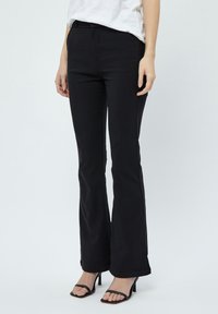 Pantaloni neri a zampa d'elefante in tessuto elasticizzato, con vita aderente e una leggera texture lucida, abbinati a eleganti sandali neri con tacco alto.