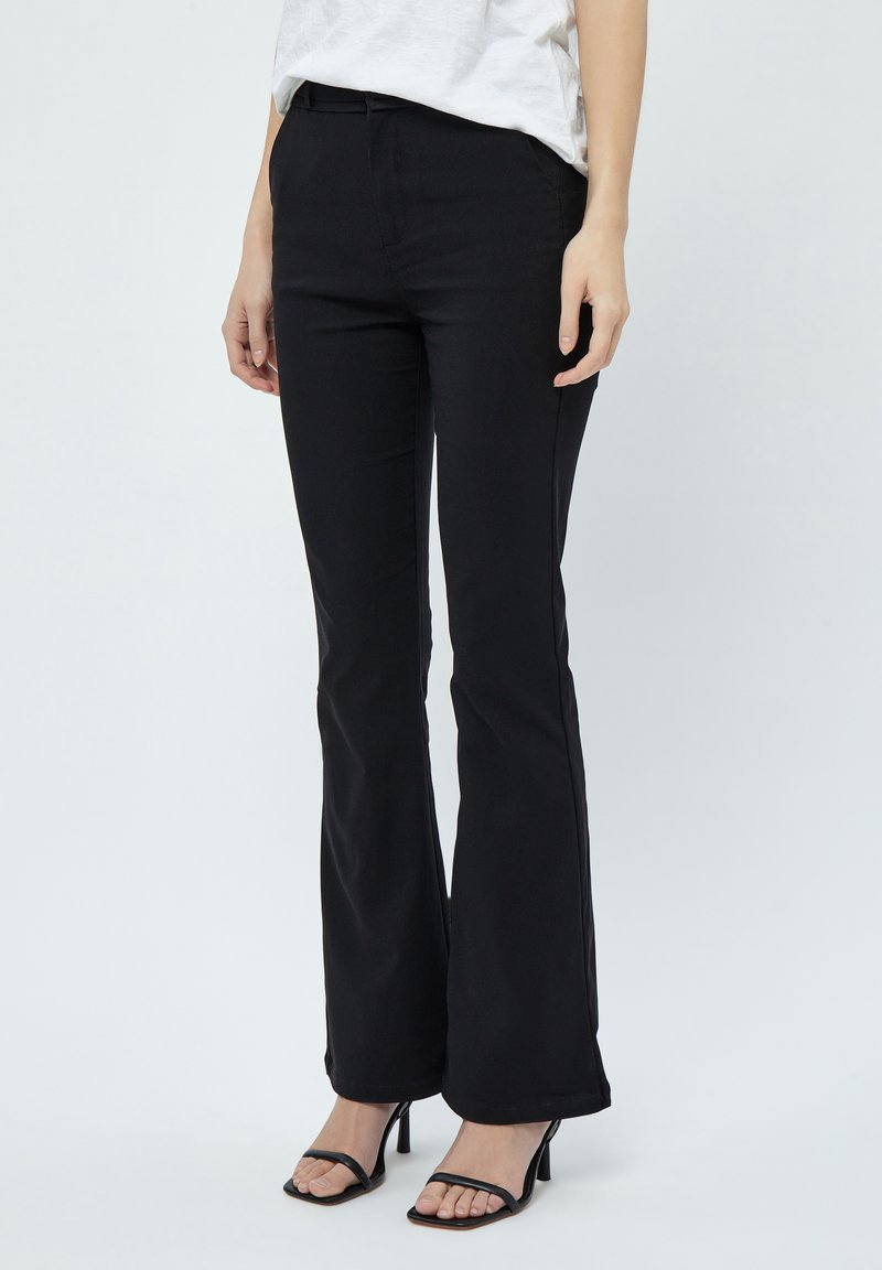 Pantaloni neri a zampa d'elefante in tessuto elasticizzato, con vita aderente e una leggera texture lucida, abbinati a eleganti sandali neri con tacco alto.