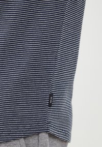 Navy and white striped fabric with a textured look, featuring a small label on the side and a slightly curved hemline.