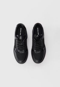 Sneakers neri in pelle e rete con punta rotonda, design con lacci, collo imbottito e dettaglio del logo sulla linguetta. La texture è liscia e traspirante.