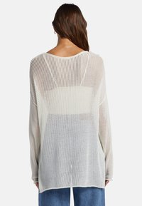 Leichter, offen gestrickter Pullover in Creme mit vertikalen Streifen, ausgestattet mit langen Ärmeln und einer lockeren Passform. Rundhalsausschnitt, leicht durchscheinend.