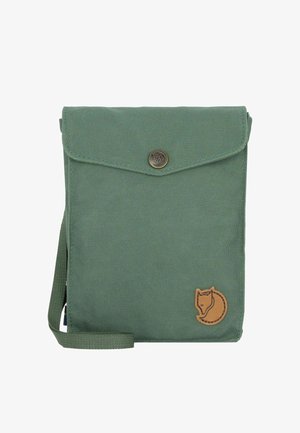 Zelená plátěná taška s klopou na zapínání, opatřená mosazným knoflíkem a koženým logem lišky. Součástí je odnímatelný popruh pro nošení.