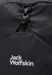 Sac à dos noir à cordon de serrage avec une surface texturée, doté d'un fermoir noir et d'un logo "Jack Wolfskin" blanc bien en évidence.