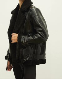 Czarna kurtka z imitacji skóry z grubym, teksturowanym czarnym kołnierzem i podszewką z baranka. Posiada zamki błyskawiczne i regulowane boczne paski.