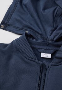 Navyblauwe zip-up hoodie met een geribbelde kraag, voorzien van een capuchon, gladde textuur en metalen drukknopen. Label geeft maat 5-6 jaar aan.