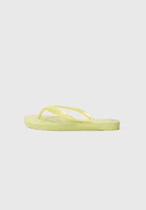 Infradito giallo con una suola testurizzata e cinturini trasparenti. Il design è semplice con una pianta piatta e uno stile minimalista.