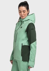 Eine zweifarbige Winterjacke in Mintgrün und Dunkelgrün. Verfügt über eine Kapuze, Reißverschlüsse und ein strukturiertes Material für zusätzlichen Wärme- und Haltbarkeit.