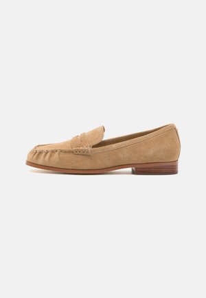 Suede loafers in light beige with a rounded toe, front strap accent, and a low wooden heel. Smooth texture and minimal stitching details.