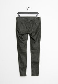 Tmavě zelené slim-fit kalhoty s hladkým povrchem, které mají dvě zadní kapsy, jemné sklady a pas s poutky na pásek.