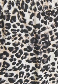 Tessuto con stampa maculata di leopardo con macchie nere e marroni su uno sfondo crema. Presenta una texture morbida e una leggera lucentezza, progettato per un capo fluente.