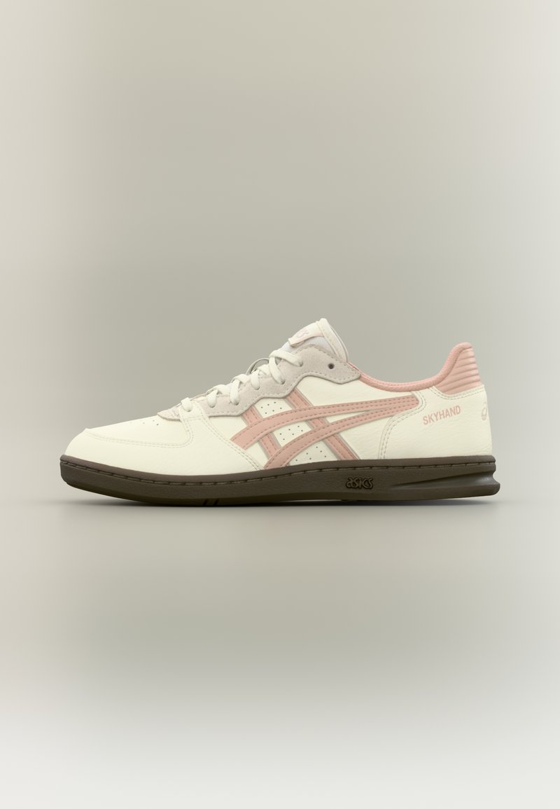 Balti ir šviesiai rožiniai sportiniai bateliai su perforuota oda, guminėmis padų dalimis ir žemu viršumi. Ypatingos savybės: kontrastingos juostelės ir firminiai akcentai.