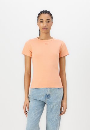 Peach-colored short-sleeve t-shirt in stretchy material with a round neckline, featuring a small logo at the chest and a fitted design.