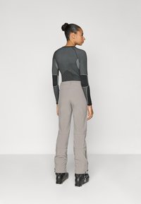 Sportlik tumedat halli värvi pikkade varrukatega särk tekstuursete aktsentidega, kombineeritud heledate hallide suusapükstega, millel on tõmblukud ja voolujooneline disain. Mustad saapad.