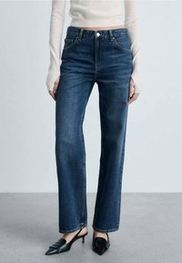 Pantalones de mezclilla de pierna ancha en azul oscuro con cintura alta, diseño de cinco bolsillos y cierre frontal con botón. Terminado con un dobladillo prolijo.