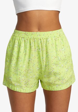 Green floral shorts with an elastic waistband, featuring a scattered pattern of white flowers and red accents on a lightweight fabric.