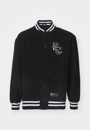 Juodas kordūrinis švarkas su baltais dryžuotais šiurkščiais apykaklės ir rankovių kraštais, turi logotipo užsegimą krūtinėje ir snapelių užsegimą.