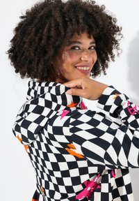 Geruite hoodie in zwart, wit en felle kleuren; met sterren- en lipaccenten; van zachte stof en een losse pasvorm.