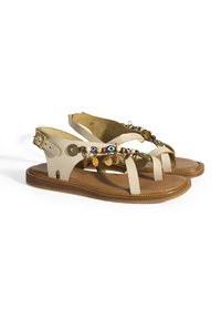 Beige leren sandalen met een platte zool, meerdere banden, decoratieve kralen en metalen accenten. Verstelbare enkelgesp voor een goede pasvorm.