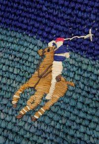 Vävt väggkonst som visar en häst och ryttare i brunt och beige på en texturerad blågrön bakgrund med en mörkblå övre del.