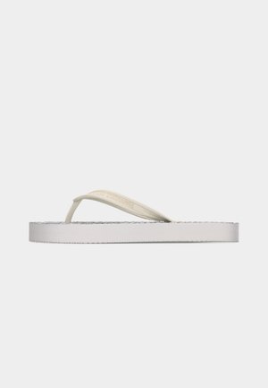 Hvit flip-flop sandal med beige stropper preget med merkevarenavnet "ARMANI EXCHANGE", vist i profil mot en ensfarget bakgrunn.