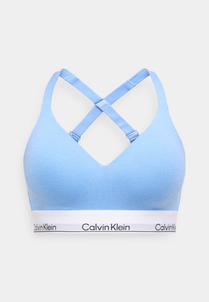 Hele sinine sportlik rinnahoidja V-kaeluse ja ristatud rihmadega. Valge elastse bändi peal mustas kiri "Calvin Klein". Sile tekstuur.