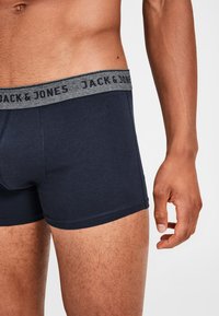 Marineblaue Baumwoll-Boxershorts mit einem grauen Bund, auf dem der Text "JACK & JONES" steht. Sie sitzen eng an und haben einen geraden Schnitt sowie gestickte Details.