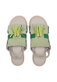 Sandali verde in suede con dettagli frangiati, cinturini elastici e suola beige. Presentano una superficie texturizzata e un design minimale.