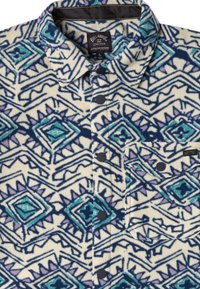Camicia in felpa con base crema, caratterizzata da un motivo geometrico blu e viola, bottoni a pressione neri e tasca sul petto.