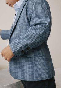 Children's blue checkered blazer with a soft texture, featuring a notched lapel, two buttons on the cuffs, and a tailored fit.