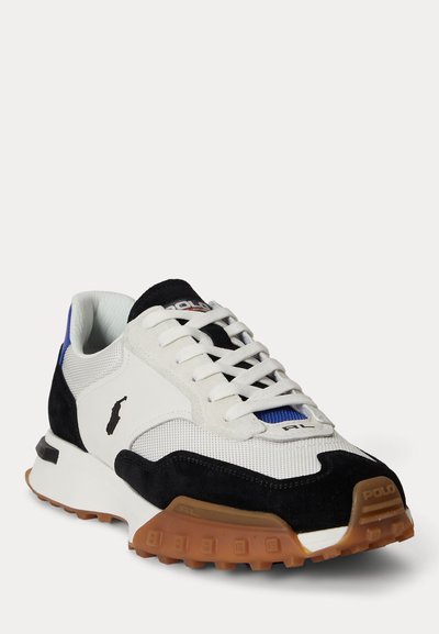 Weißer und schwarzer Polo-Sneaker mit brauner, strukturierter Sohle, weißen Schnürsenkeln, blauem Akzent unter der Zunge und Polo-Logo an der Seite.