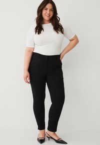 Hvid kortærmet top parret med sorte skræddersyede bukser. Bukserne har en slim fit, glat tekstur og sidelommer. Sorte hæle fuldender looket.