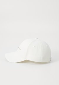 White cotton baseball cap with a curved brim, embroidered logo in light gold, and vent holes on the top for breathability.